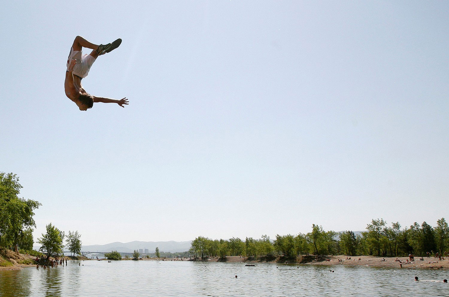 Человек прыгает в озеро, фото летнее