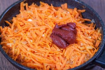 В томленную с луком морковь выкладываем томатную пасту