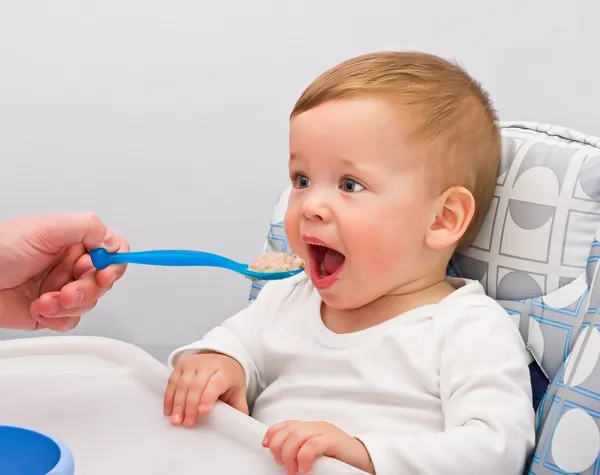 Один летний малыш ест каши — стоковое фото