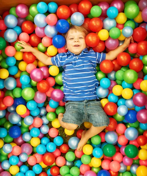 Счастливый ребенок, играя с красочными пластиковые шарики — стоковое фото