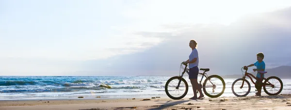 Мать и сын, ездящий на велосипеде на пляже — стоковое фото