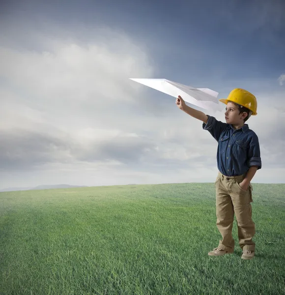 Молодой мальчик пытается лететь бумаги плоскости — стоковое фото