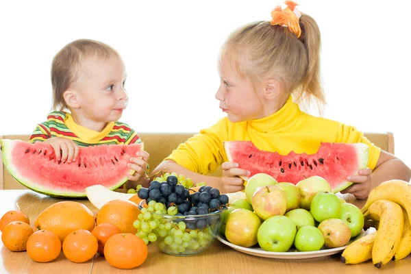 Двое детей едят фрукты на столе — стоковое фото