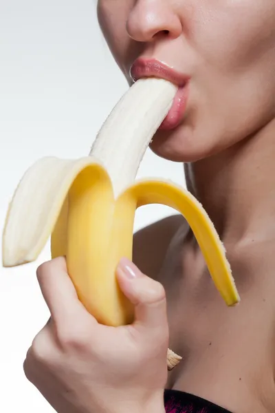 Молодая женщина кусаться банан, изолированные на белом фоне — стоковое фото