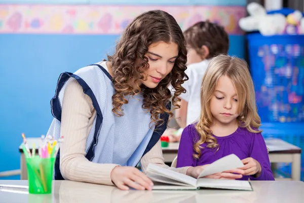 Учитель и маленькая девочка книга чтение в классе — стоковое фото