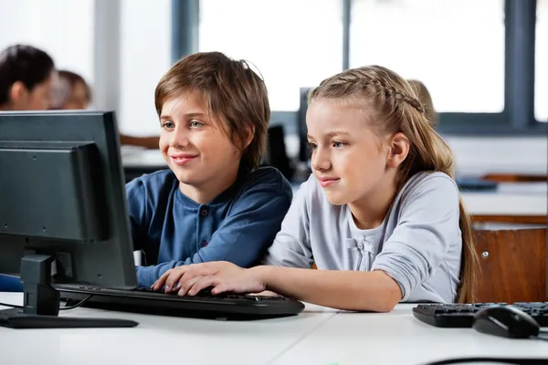 Мальчик и девочка с помощью ПК в школе компьютерной лаборатории — стоковое фото