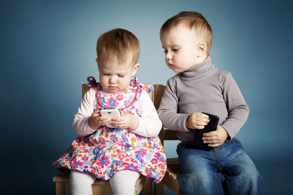 Маленький мальчик и девочка, играя с мобильных телефонов — стоковое фото