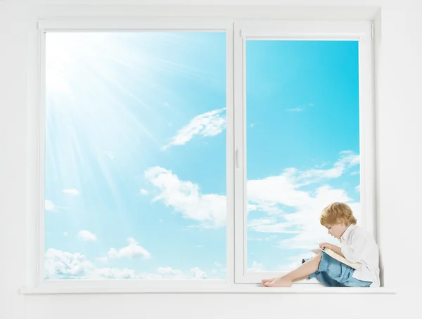 Окно солнце небо. ребенок на подоконнике, читать книгу — стоковое фото