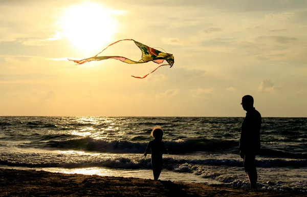 Отец и дочь летающих змей на пляже — стоковое фото