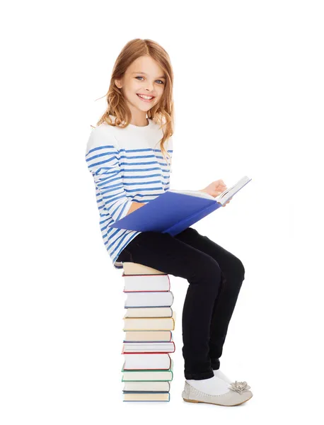 Маленькая девочка студент, сидя на стопку книг — стоковое фото