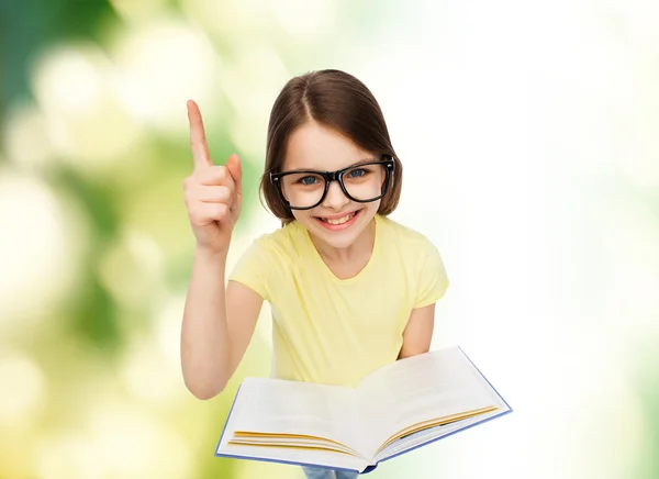 Улыбается маленькая девочка в очки с книгой — стоковое фото