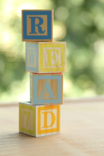 Слово «читать» цветные кубики для детей дошкольного возраста учится читать на фоне размытых — стоковое фото