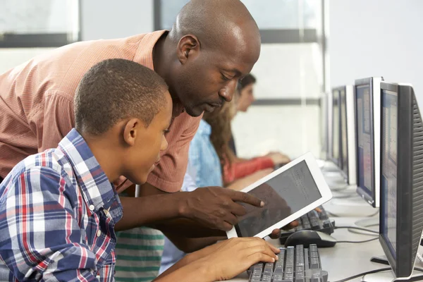 Учитель помогает мальчик использовать цифровые планшетные в компьютерном классе — стоковое фото