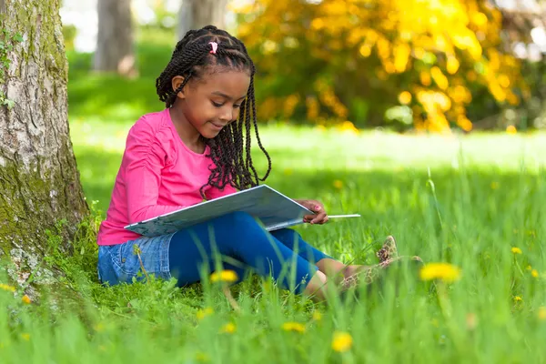 Открытый портрет милой молодой черный маленькая девочка чтение Бу — стоковое фото