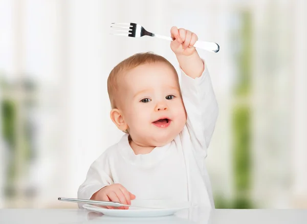 Смешно ребенка с ножом и вилкой, приема пищи — стоковое фото