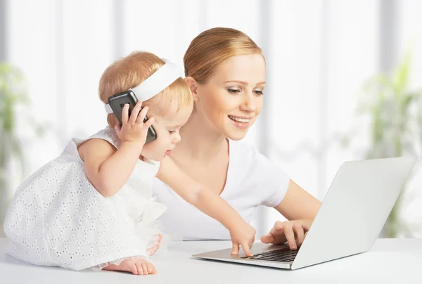 Мать с дочерью ребенок работает с компьютером и телефоном — стоковое фото