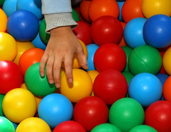 Рука ребенка с пластырем, который принимает цветные шары — стоковое фото