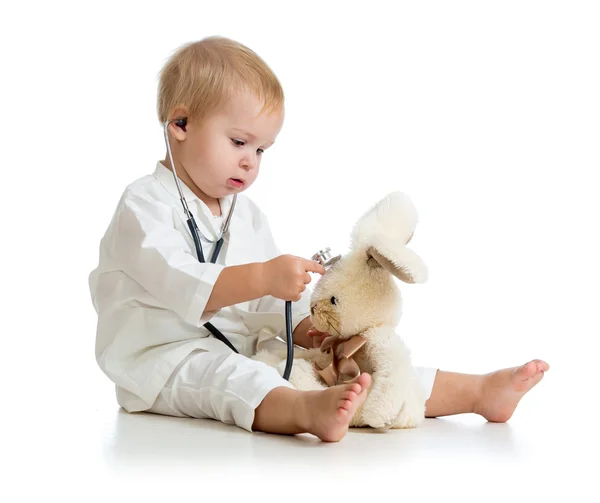 Восхитительный ребенок с одеждой доктора и плюшевого мишки по белому — стоковое фото