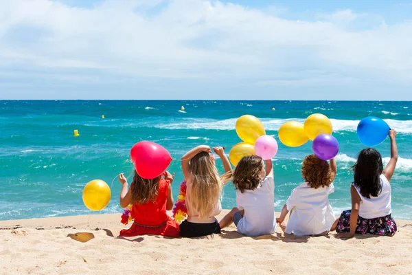 Дети, сидя на пляже с цветом шаров — стоковое фото