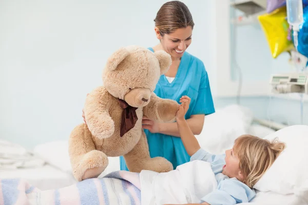 Медсестра, показаны плюшевого мишку с ребенком — стоковое фото