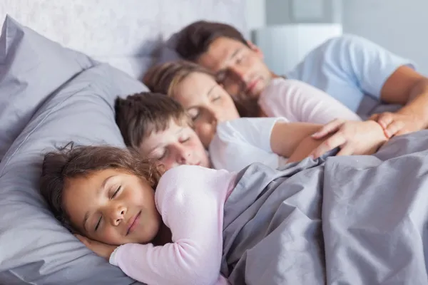 Милая семья спит в постели — стоковое фото
