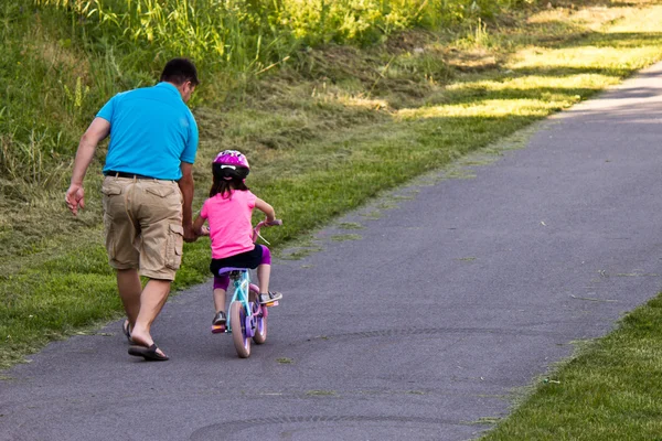 Обучение езде на велосипеде с отцом ребенка — стоковое фото