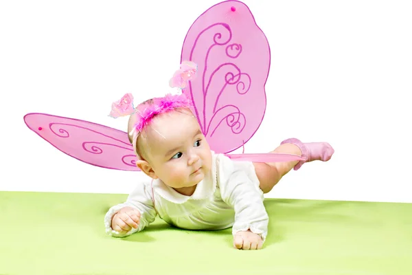 Девочка довольно ребенок, одетый в костюм бабочки на зеленом фоне понятие детства и праздника — стоковое фото