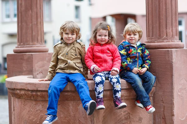 Трех братьев и сестер, сидели на фонтане в городе — стоковое фото