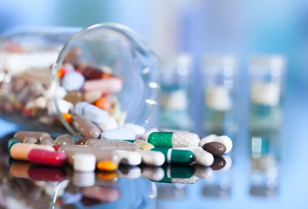 Красочные таблетки, капсулы и таблетки на синем фоне — стоковое фото