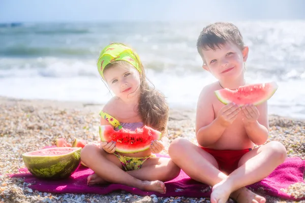 Дети едят арбуз на пляже — стоковое фото