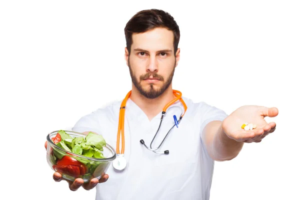 Красивый мужской доктор, показаны таблетки и салат — стоковое фото