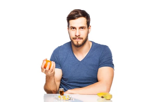 Человек, имеющий в передней, таблетки и фрукты, выбор между ними — стоковое фото