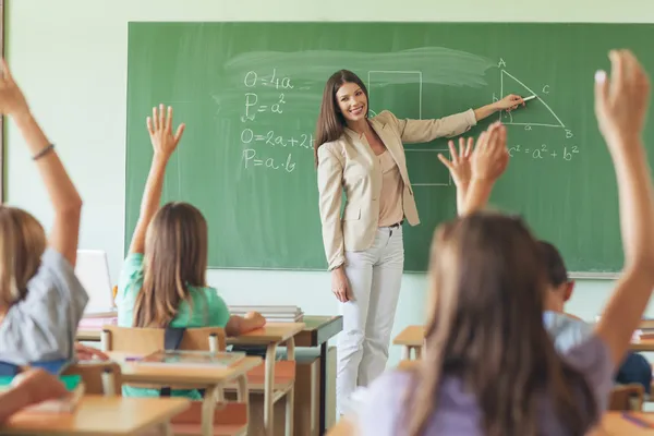 Студенты, поднимая руки в Урок математики — стоковое фото