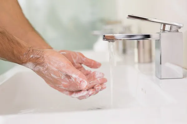 Мытье рук с мылом под струей воды в ванной комнате раковина — стоковое фото