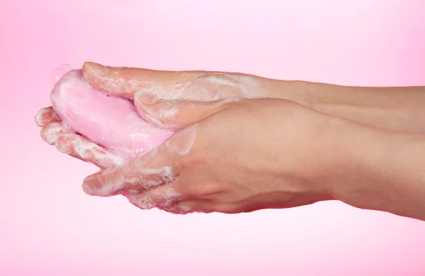 Женщина моет руки о soap на розовом фоне — стоковое фото