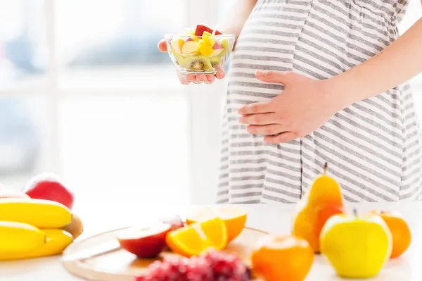 Беременная женщина, держащая фруктовый салат — стоковое фото