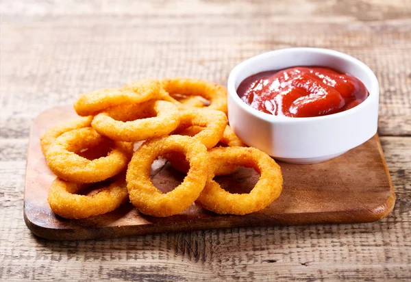 Луковые кольца с кетчупом — стоковое фото
