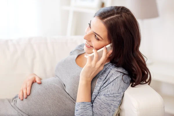 Счастливый беременная женщина, призывая на смартфоне на дому — стоковое фото
