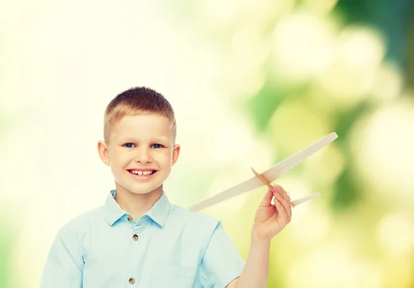 Улыбающийся мальчик, держащий модель деревянный самолет — стоковое фото