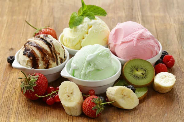 Ассорти мороженого (клубника, банан, мята, шоколад) и свежие ягоды на деревянный стол — стоковое фото