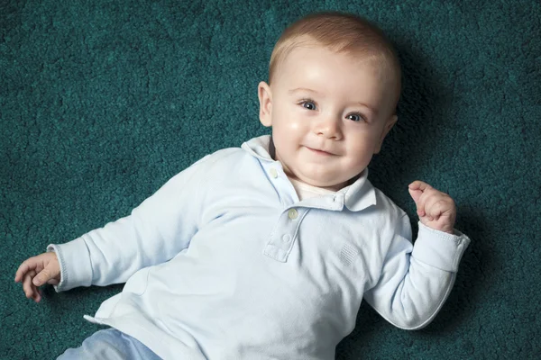 Очаровательны младенца, лежащего на синий ковер — стоковое фото