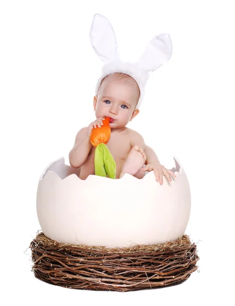 Happy baby девушка Пасхальный кролик сидел в Пасхальное яйцо-гигант ест морковь — стоковое фото