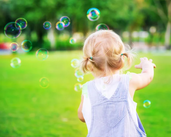 Baby девушка играть с мыльных пузырей — стоковое фото