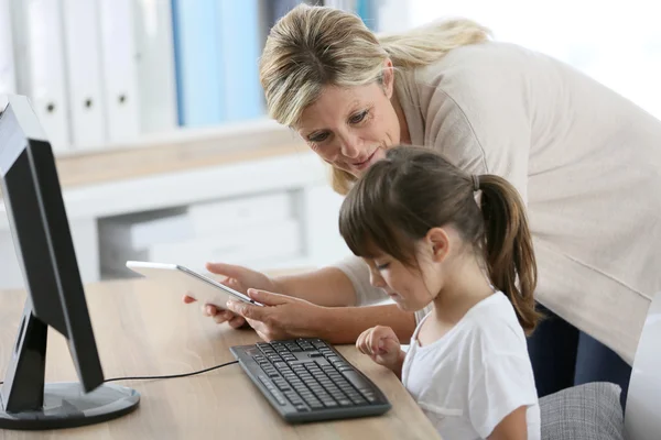Учитель с девочкой, использующей компьютер и таблетку — стоковое фото