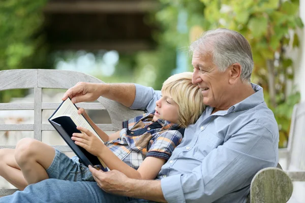 Чтение книги дед с внуком — стоковое фото