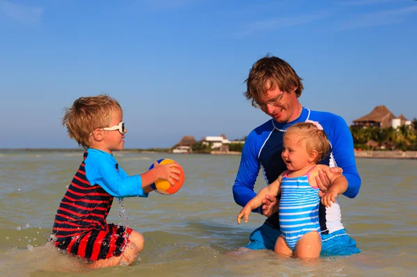 Отец и дети, играя мячом на море — стоковое фото