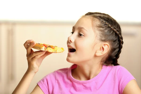 Маленькая девочка ест пиццу дома — стоковое фото