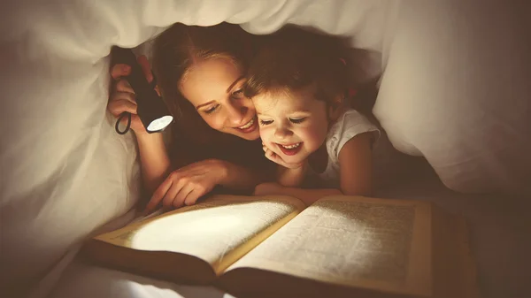 Семейного чтения перед сном. Мама и ребенок чтение книги с фонар — стоковое фото