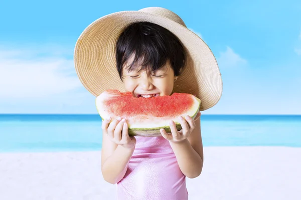 Ребенок ест арбуз на берегу моря — стоковое фото