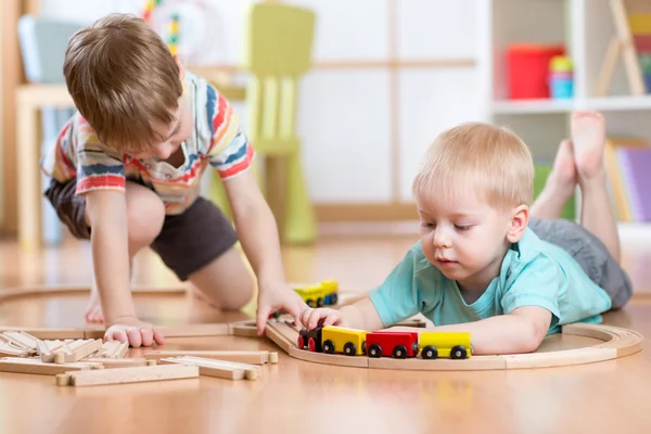 Симпатичные дети играют с деревянный поезд. Малыш дети играют с блоков и поезда. Мальчики, строительство железной дороги игрушку дома или детский сад — стоковое фото